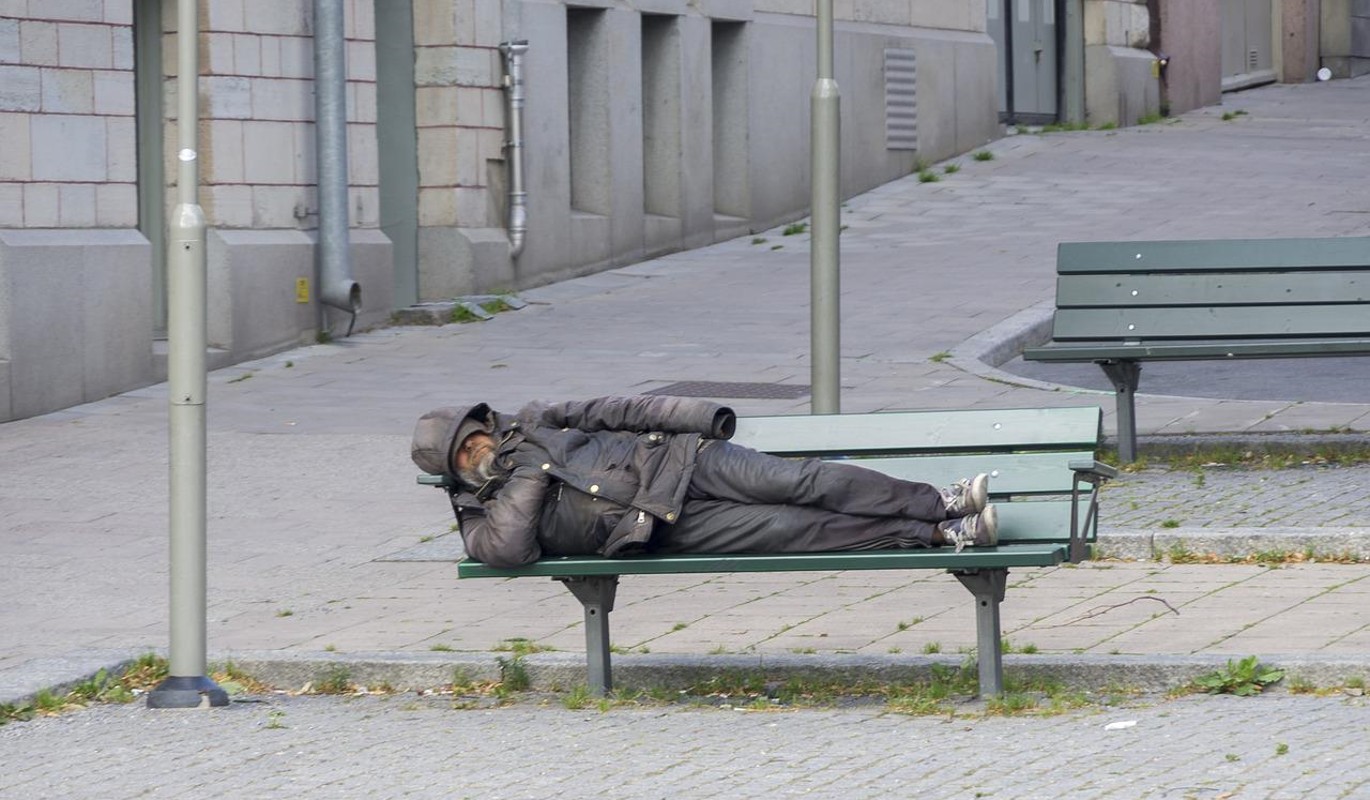 Бездомный спит на скамейке